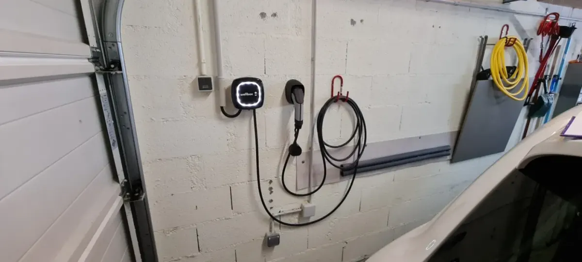 Borne de recharge installée sur un mur de garage avec un cheminement de câble soigné